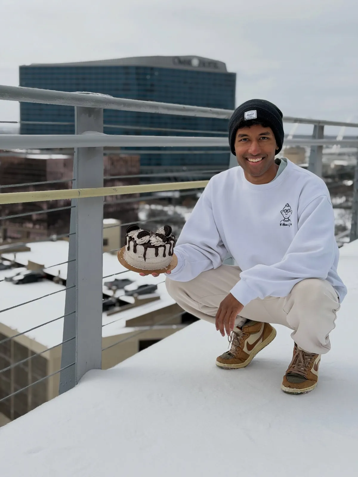 Sai crouching on a rooftop with a cake